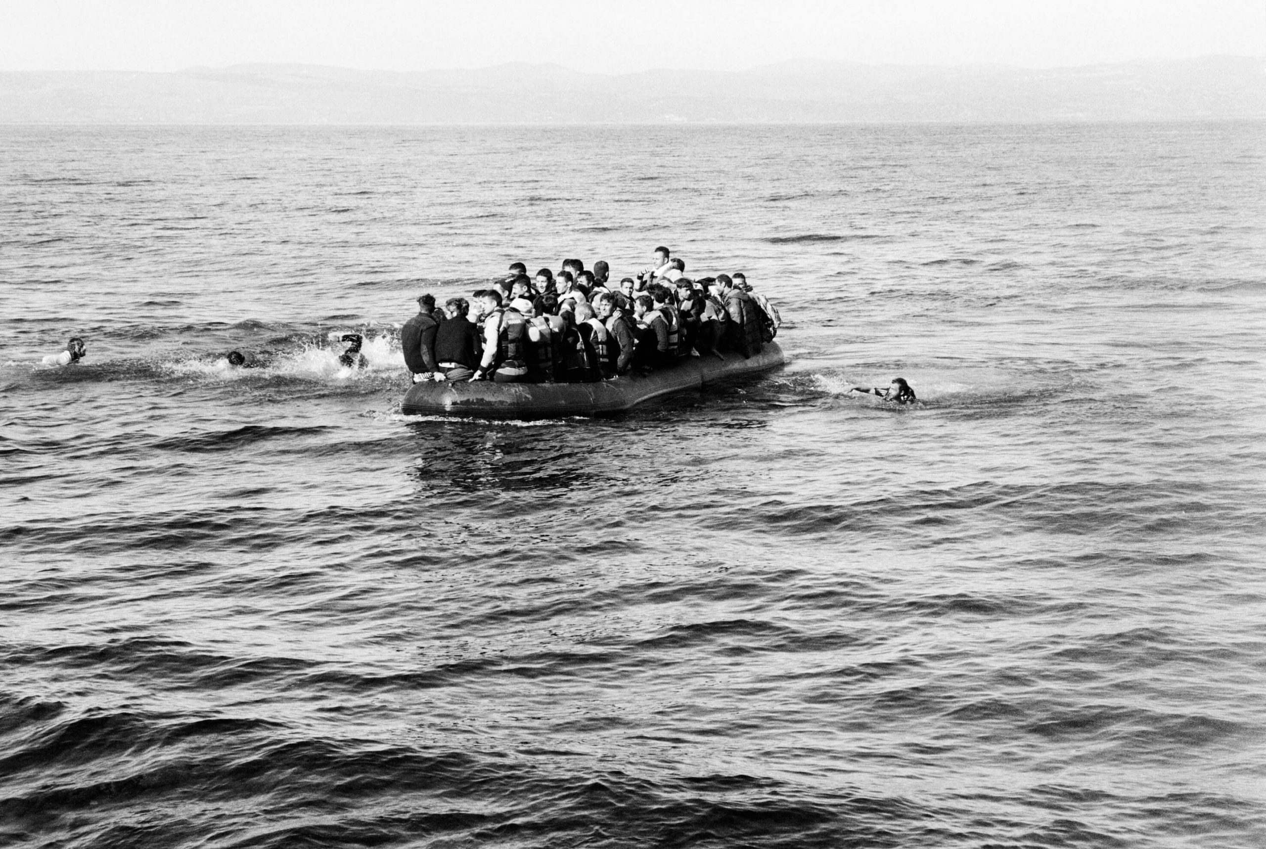 An overcrowded boat of refugees heads to the shore.